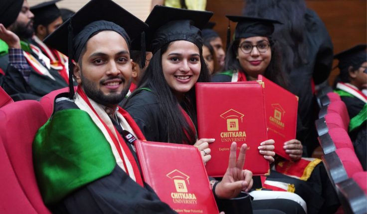 Four students in convocation gowns proudly showing their degrees, symbolizing the Benefits of Earning an MBA and the career opportunities that come with it.