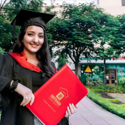 A female student smiling and proudly holding her MBA degree after completing a fully residential MBA program in India.