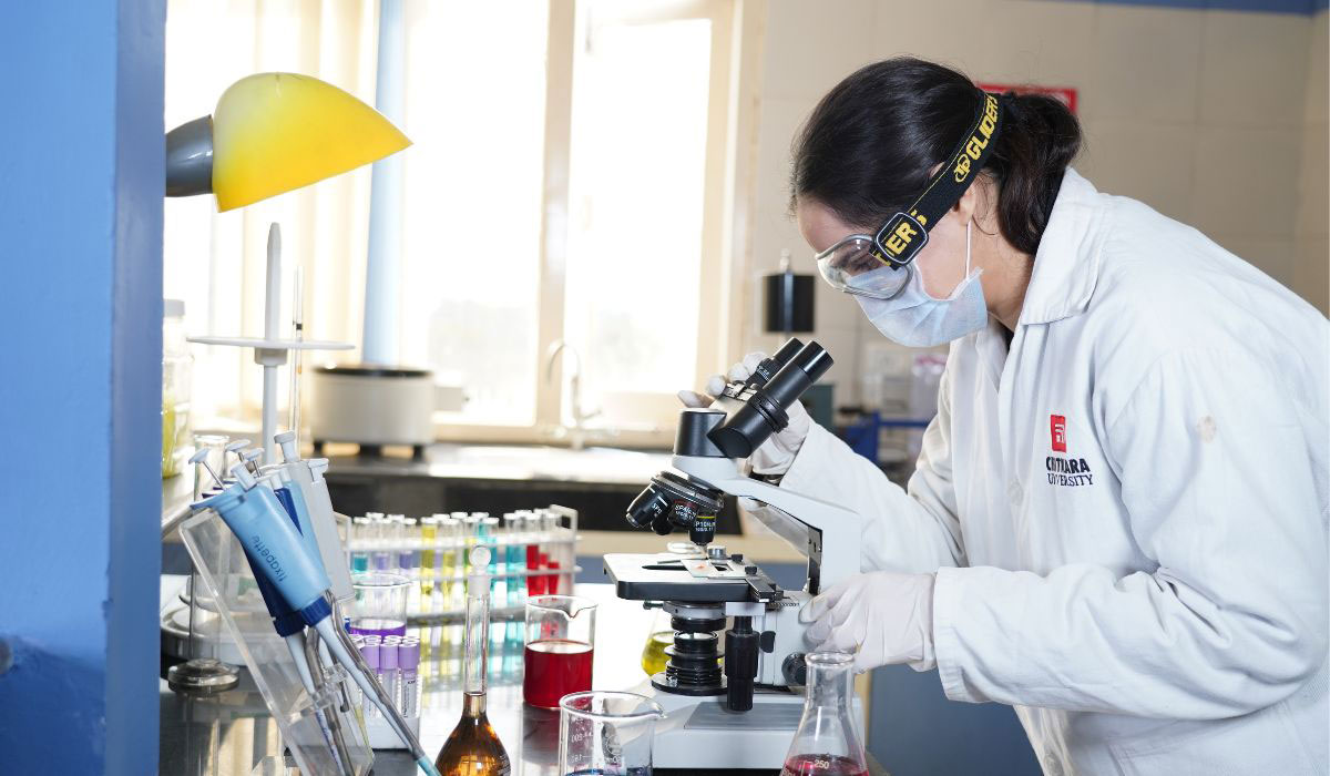 A pharmacy student looking through a microscope, gaining hands-on experience vital for M.Pharm and Pharm.D programs.